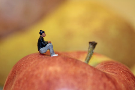 miniature people sitting on a red apple, concept of healthy eatingの写真素材