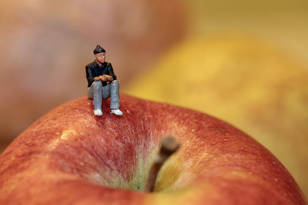 Miniature people sitting on apple. Selective focus and shallow depth of fieldの写真素材