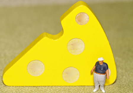 Miniature people: fat man and cheese on a yellow backgroundの写真素材