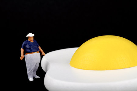 Miniature people : Chef with egg on black background, Healthy food conceptの写真素材