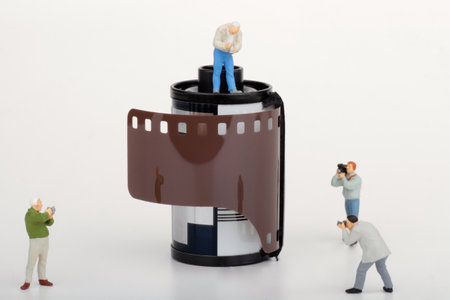 Miniature people : photographer and cameraman with film strip on white background