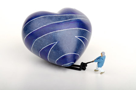 miniature man and woman sitting on a heart-shaped blue stoneの写真素材
