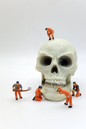 Miniature people : Workers repairing skull on white background, Halloween concept