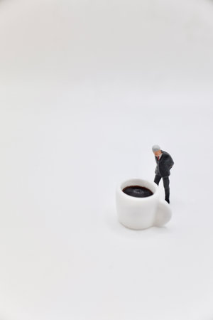 Miniature people : Businessman standing on coffee cup with white background