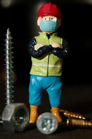 Miniature people construction worker in protective mask against COVID-19 virusの写真素材