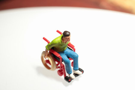 Miniature people: Wheelchair and man on the white background.の写真素材