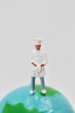 Miniature people : Chef standing on the ball over white backgroundの写真素材