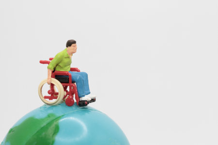 Miniature people: Wheelchair and disabled man on the globe.の写真素材