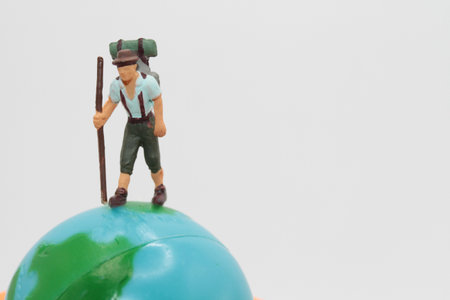 Miniature people : Hiking backpacker standing on green globe.の写真素材