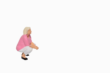 Miniature people: Senior woman sitting on the floor with white backgroundの写真素材