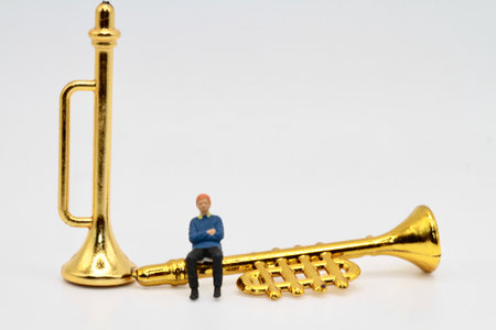 miniature people playing the trumpet on white background with copy space.
