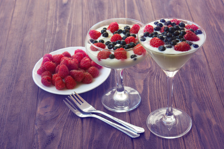 yogurt dessert with raspberries and blueberries in glassesの写真素材