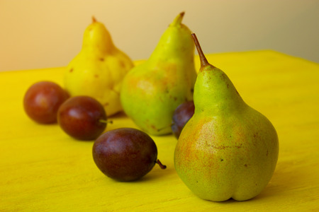 ripe pears on rustic table. Ripe fruits of  plums and pear  on rustic background. Fresh pears over wooden background. fresh ripe organic pears and plums  on a rustic wooden tableの写真素材