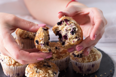 Closeup female hands  and cup cake with fresh berries. Blueberry muffins with fresh berries. homemade blackberry muffins の写真素材
