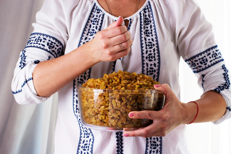 Woman's hands holding a bowl of raisins. Sweet raisins in the bowlの写真素材