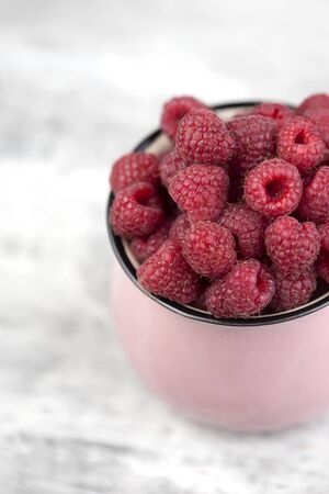 Enamel Mug with raspberries. Pink Enamel cup with raspberries. fresh raspberry in enamel cup over...