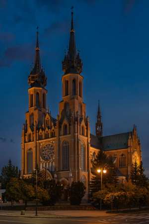 A stunning night view of a beautifully illuminated neo-Gothic church captured during the blue hour. The twin spiers and intricate architectural details are highlighted by warm lighの写真素材