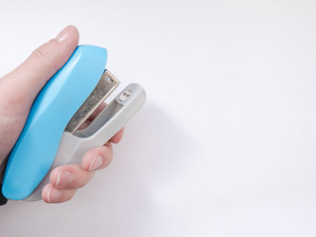 A blue paper stapler is held in your hand. Blue stapler of the paper. Stapler in hand.の写真素材