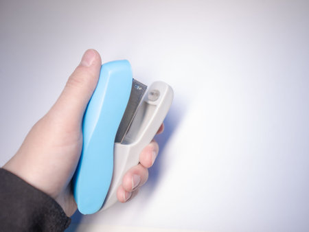 A blue paper stapler is held in your hand. Blue stapler of the paper. Stapler in hand.の写真素材