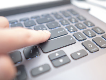 Man by his finger almost has pressed enter button on steel keyboardの写真素材