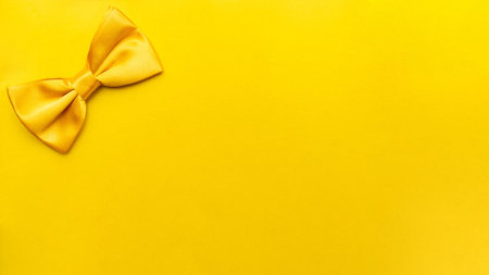 Close-up of a yellow bow tie on a yellow background with space for textの写真素材
