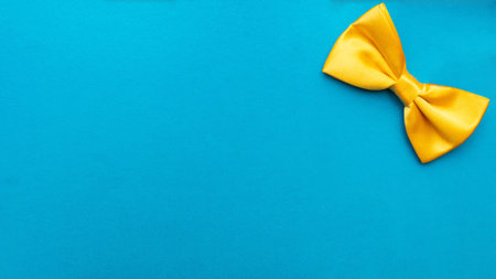 Close-up of a blue bow tie on a yellow background with space for the textの写真素材