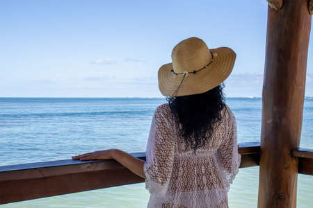 Relaxed sexy young woman enjoying the beautiful turquoise horizon of the Caribbean Sea from a pier on the beach.の写真素材