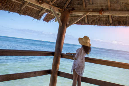 Pensive woman on the pier looking at the turquoise Caribbean sea, while enjoying a warm and relaxing atmosphere.の写真素材