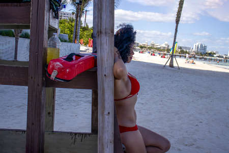 Sexy lifeguard leaning on the chair with the lifeguard ready to help the swimmers, in the Caribbean Sea with its beautiful turquoise colors and the tropical sun in a natural and beautiful place. baywatch.の写真素材