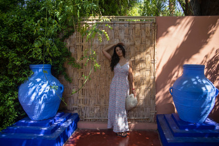 Young tourist on a wooden wall and a blue environment of the Majorelle garden in Marrakech (Morocco).の写真素材