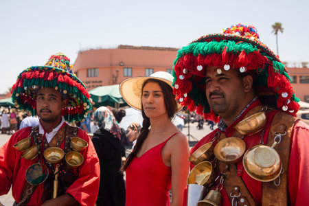 Marrakech, Morocco - November 9, 2022: Female tourist with two water vendors in Marrakech square, this kind of commercials are very common, traditional and a tourist attraction in this Arab city.のeditorial素材