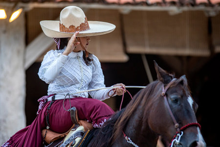Beautiful Mexican female equestrian show with traditional hat on a high breed Aztec horse changing from gallop to trot, this is a unique and incredible show at Xcaret Park in Mexico.の写真素材