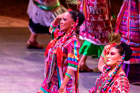 Xcaret, Mexico - January 27, 2023: Beautiful women performing the folkloric dance of the pineapple flower at Xcaret park in the middle of the tropical jungle of the Mayan Riviera in Mexico.のeditorial素材