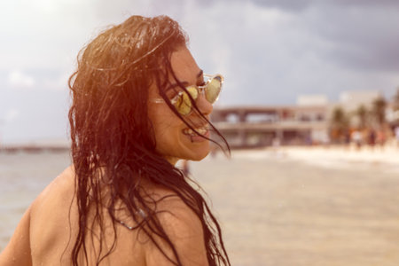 Young woman with sexy smile under the tropical sun enjoying the Caribbean sea on the white sandy beach of Playa del Carmen in the famous Mayan Riviera of Mexico, an ideal sun and beach vacation spot.の写真素材