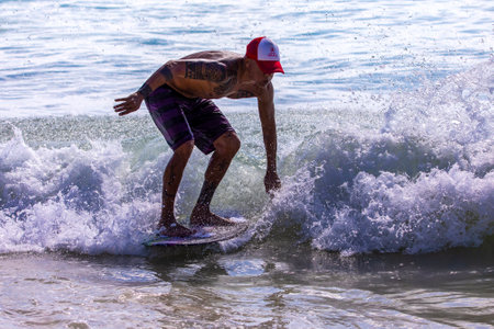 Playa del Carmen, Mexico - March 12, 2023: Surfer surfing the waves of the Caribbean Sea with his small skimboard, an ideal water sport for the beach shore and just like surfing.のeditorial素材