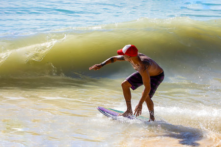 Playa del Carmen, Mexico - March 12, 2023: Man enjoying his skimboarding of the waves on the shores of the Caribbean Sea, which consists of surfing the waves with a board smaller than a surfboard.のeditorial素材