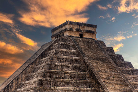The pyramid of Chichen Itza in honor of the God Kukulkan under a beautiful tropical orange sunset, this is the feathered serpent of the Mayan civilization.の写真素材