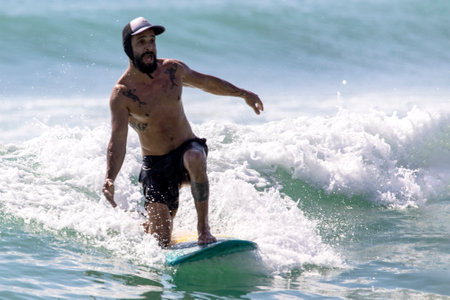 Playa del Carmen, Mexico; May 9, 2023: A sporty man enjoying his board in the warm and beautiful waves of the Caribbean Sea, this is an elite athlete surfing under the tropical sun.のeditorial素材