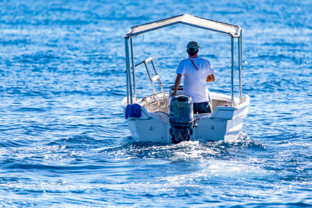 Angler taking his small boat out to sea to fish while enjoying the marine life and the bright...
