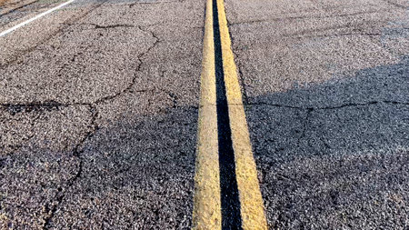 Yellow line of road markings on the road pavement, on the highway that crosses the desert in the Mojave from Los Angeles in California, to Las Vegas in Nevada.の写真素材