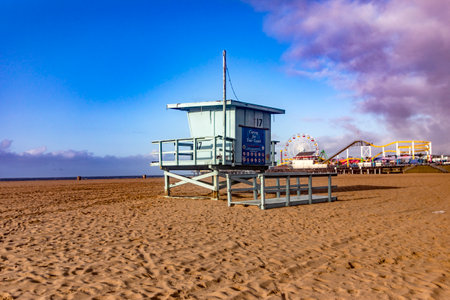 Photograph of a lifeguard hut with the Santa Monica Pier amusement park in the background and over the Pacific Ocean, on the west coast of California in the United States of America.の写真素材