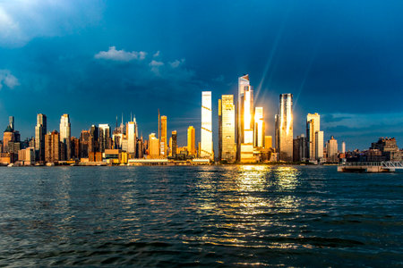 Wonderful skyline of New York and Big Apple seen from a viewpoint on the Hudson River, under a sunset and the sun's rays reflecting on the buildings.の写真素材