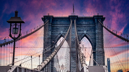 Walking across the famous, incredible and wonderful Brooklyn Bridge that connects the boroughs of Manhattan and Brooklyn in New York City (USA) an incredible sunset.の写真素材
