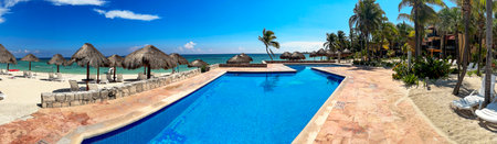 Panoramic view of a beautiful pool of a luxurious white sandy beach resort, with the turquoise and crystal clear sea of the Caribbean Sea in Mexico.の写真素材