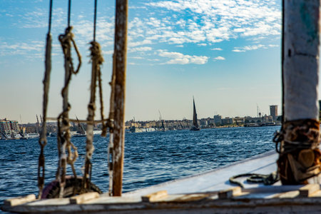 See a traditional Nile river felucca, navigating the ancient pharaonic river. This photo shows the timeless beauty of a felucca sailing down the historic river.の写真素材