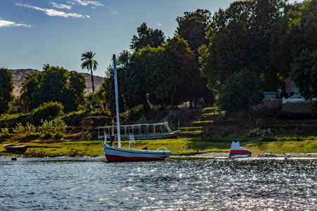 A Nile felucca docked and resting on the serene shore. This peaceful scene captures the beauty of a traditional felucca docked alongside Egypt's pharaonic river.の写真素材