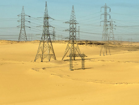 Explore the sight of High Voltage Electricity Towers Through the Desert. Witness the power lines stretching across arid landscapes, connecting distant communities.の写真素材