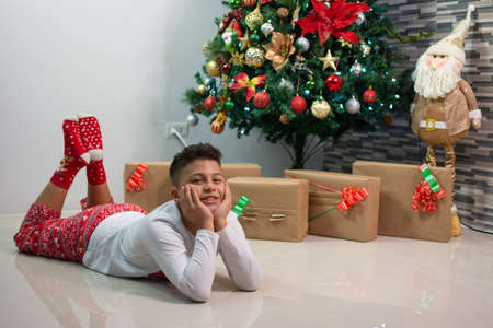 A very happy child in the living room of his house with the Christmas tree waiting to open the...