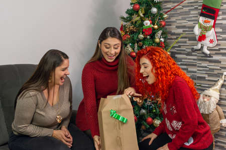 Three happy friends opening a gift very surprised at Christmasの写真素材