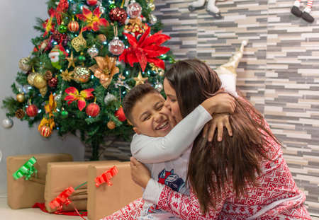 A very happy mother hugging and kissing her son at Christmasの写真素材